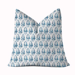 May include: A white throw pillow with a blue and white geometric pattern. The pattern features a repeating design of stylised leaves.