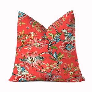 May include: A coral red throw pillow with a floral and animal print. The print features leopards, birds, and flowers in shades of pink, blue, green, and white.