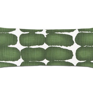 May include: A long, rectangular cushion with a white background and a green abstract pattern. The pattern is made up of irregular shapes that resemble stones or pebbles.