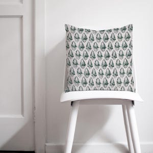 Puede incluir: Una silla blanca con un coj&iacute;n estampado en verde y blanco. La silla es de madera y tiene un coj&iacute;n blanco.
