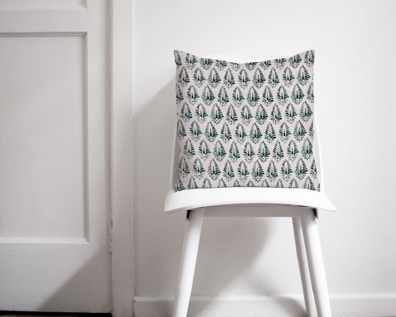 Puede incluir: Una silla blanca con un coj&iacute;n estampado en verde y blanco. La silla es de madera y tiene un coj&iacute;n blanco.