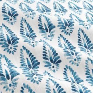 May include: White fabric with a repeating pattern of blue paisley shapes. The paisley shapes are made up of small, swirling lines.