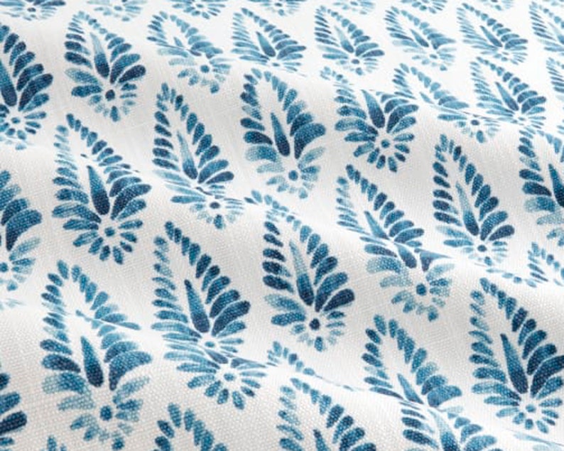 May include: White fabric with a repeating pattern of blue paisley shapes. The paisley shapes are made up of small, swirling lines.