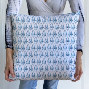 May include: A white cushion with a blue and white geometric pattern. The pattern is a repeating design of stylised teardrop shapes.