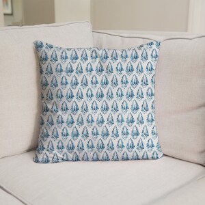 May include: A white sofa with two cushions. The cushion in the front has a blue and white patterned design.