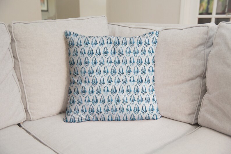 May include: A white sofa with two cushions. The cushion in the front has a blue and white patterned design.