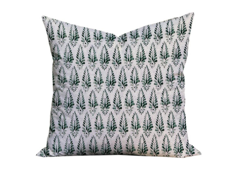 Puede incluir: Una almohada blanca con un patr&oacute;n de hojas verdes. La almohada est&aacute; hecha de una tela suave y c&oacute;moda y tiene un brillo sutil.