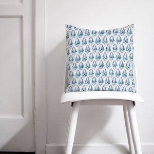 May include: A white chair with a blue and white patterned cushion. The cushion has a repeating pattern of blue teardrop shapes on a white background.