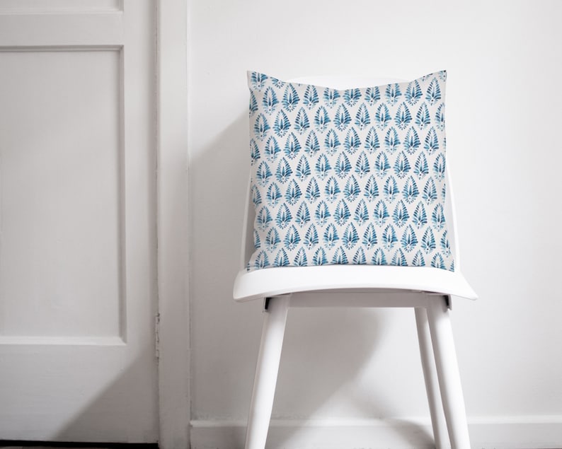 May include: A white chair with a blue and white patterned cushion. The cushion has a repeating pattern of blue teardrop shapes on a white background.