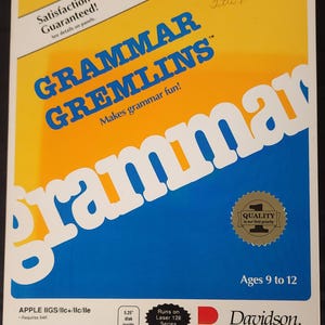 May include: A vintage computer software box for "Grammar Gremlins." The box features a blue and yellow design with the title in large blue letters. It includes the text "Makes grammar fun!" and "Ages 9 to 12." The box also states it runs on Laser 128 Series.