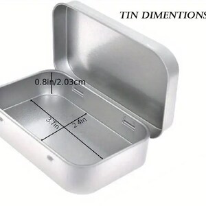 May include: A silver metal rectangular tin with a hinged lid. The tin measures 9.4 cm by 6.1 cm and is 2.0 cm deep.