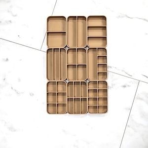 May include: A set of nine brown wooden drawer organizers with various compartment sizes. The organizers are arranged in three rows of three, with the top row having one large compartment, the middle row having two compartments, and the bottom row having three compartments.