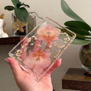 Blommig tvålkopp i harts / smyckesbricka med guldflingor, pressade orkidéblommor och vita babyandedräkter