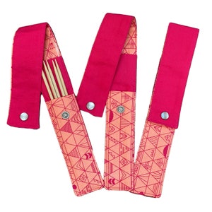 May include: Three pink fabric cases with geometric patterns. Each case has a snap closure and one case holds a set of four wooden knitting needles.
