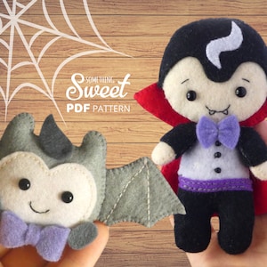 May include: Two felt Halloween plushies: a vampire and a bat. The vampire has a black cape with a red lining, a purple bow tie, and black trousers. The bat is grey with a purple bow tie. The image includes the text "Something Sweet PDF Pattern".