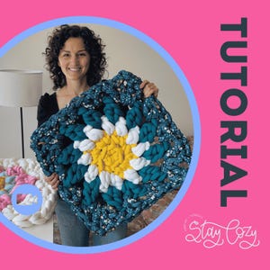 May include: A large, square, crocheted blanket in a granny square pattern. The center is yellow, surrounded by white, and teal with a floral print. The word "TUTORIAL" is vertically displayed on a pink background. The text "Stay Cozy" is in the lower right corner.