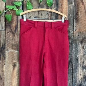 May include: A pair of red pants with a straight leg and a slightly flared hem. The pants have a zipper fly and belt loops.