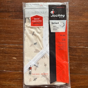 Op de afbeelding: Een verpakking Jockey-slips met een libellenprint. De slips zijn beige met een patroon van libellen en een lichtgrijze tailleband. De verpakking bevat de tekst "Special Long-Lasting Waistband".