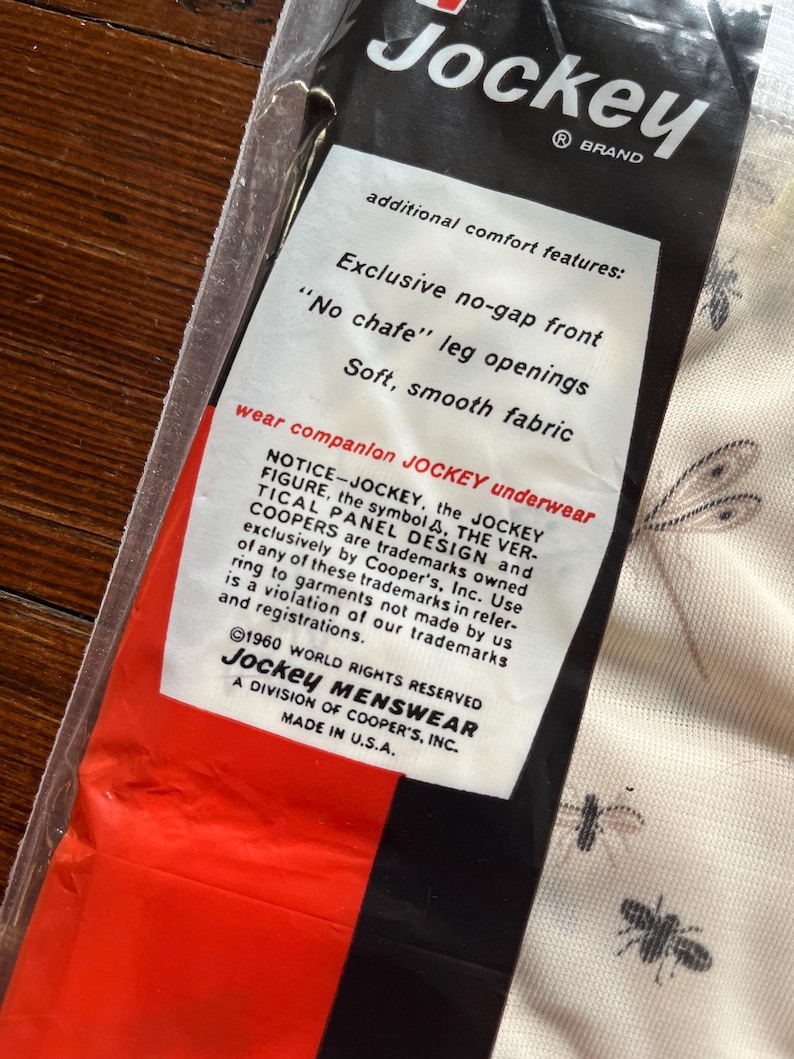 Op de afbeelding: Een verpakking van Jockey-ondergoed. De verpakking is zwart, rood en wit, met de tekst 'Jockey' en 'additional comfort features'. Het label benadrukt kenmerken zoals een naadloze voorkant en zachte stof. Gemaakt in de VS.