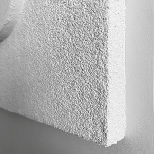 May include: Close-up of a white textured wall with a rough, grainy surface.