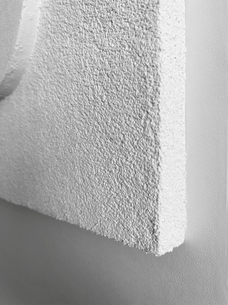 May include: Close-up of a white textured wall with a rough, grainy surface.