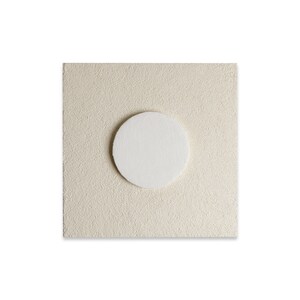 May include: A white circle on a beige textured background.