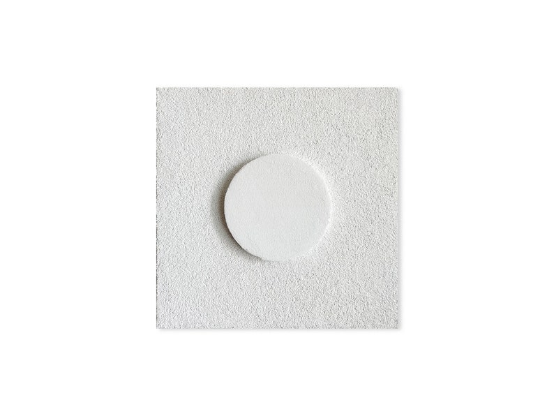 May include: A white, textured, square-shaped tile with a round, white circle in the center.
