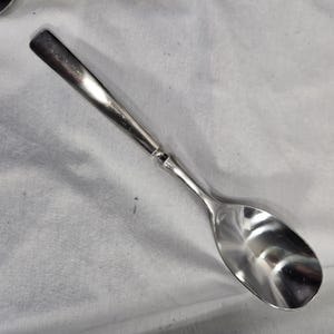 May include: A silver spoon with a long, slender handle and a rounded bowl.