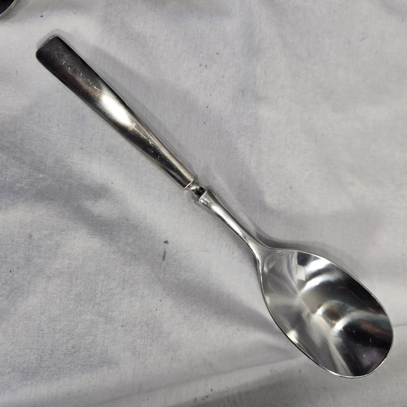 May include: A silver spoon with a long, slender handle and a rounded bowl.