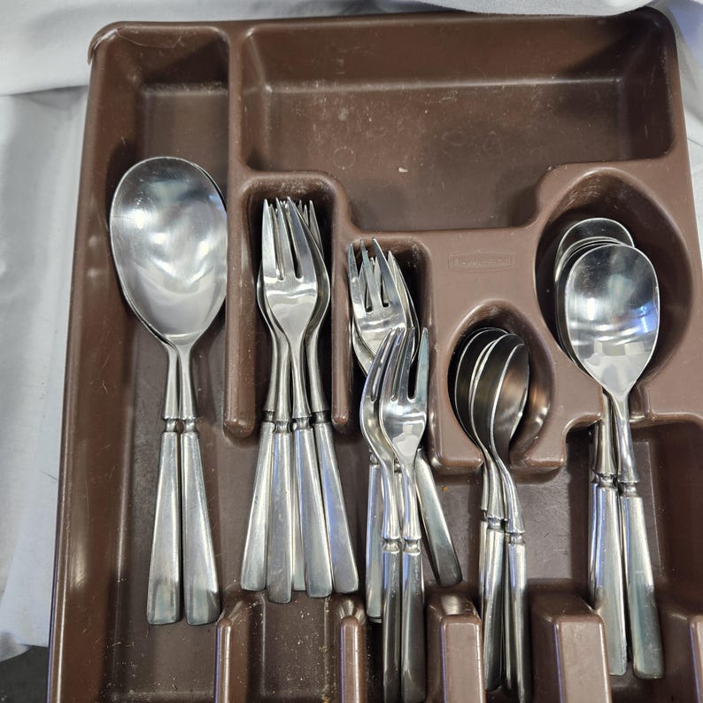 May include: A brown plastic cutlery tray with a set of silver forks and spoons. The tray has a label that says "Premiere."