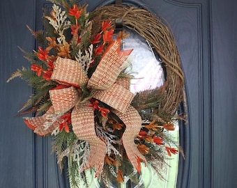 May include: A fall-themed wreath with a burlap bow and orange and brown accents hangs on a blue door with a silver door handle and a keypad lock.