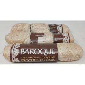 May include: Three skeins of off-white Baroque super mercerized colorfast crochet cotton yarn. Each skein features a brown paper label with white text reading Baroque, Super Mercerized, Colorfast, and Crochet Cotton, plus a white lace pattern.