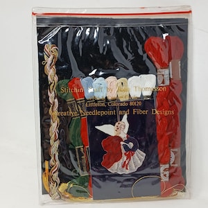 May include: A clear plastic package containing embroidery supplies. The package includes spools of red, green, and blue thread, along with a decorative angel design. The text "Stitchin Stuff by Thomasson" is visible.