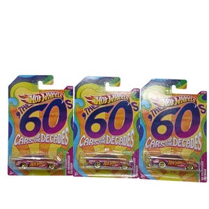 May include: Three Hot Wheels die-cast toy cars from the '60s Cars of the Decades series. Each car is in its original packaging, featuring a psychedelic design with the text "The 60's" and "Cars of the Decades". The cars are a metallic pink color.