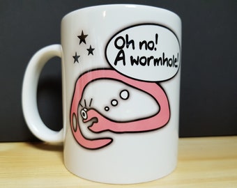Könnte beinhalten: Weiße Keramiktasse mit einem rosafarbenen Wurmloch-Design und dem Text "Oh nein! Ein Wurmloch!" in einer Sprechblase. In der oberen linken Ecke befinden sich drei schwarze Sterne.