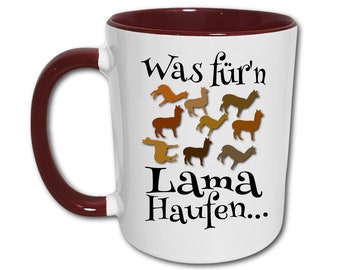 May include: White ceramic mug with a maroon handle and rim. The mug has a graphic of several brown alpacas and the text "Was für'n Lama Haufen..." printed on it.