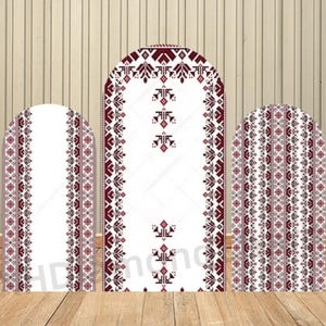 May include: Three white arched panels featuring a traditional embroidered design in burgundy and grey. The panels are set on a wooden surface, with a light brown wooden background.