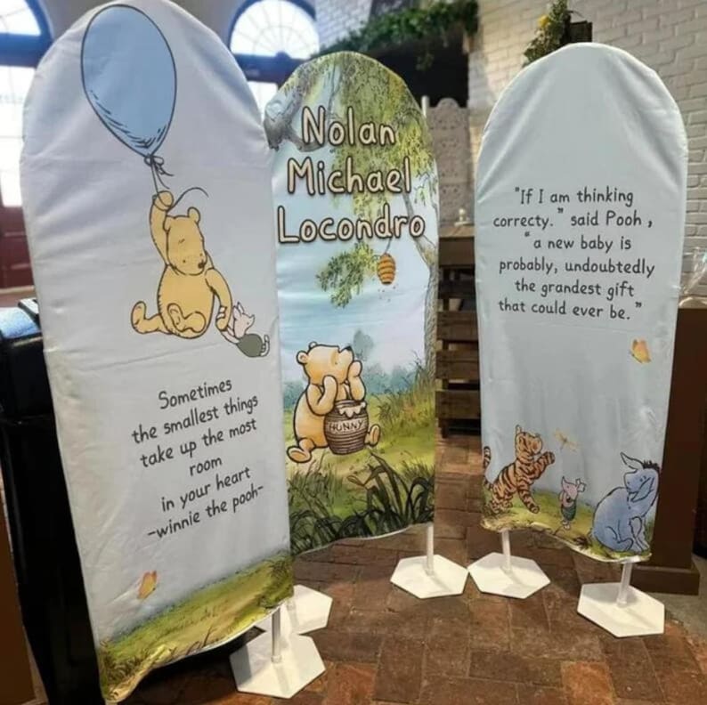 May include: Three arched fabric display banners featuring Winnie the Pooh characters. The left banner shows Pooh with a balloon and a quote. The center banner displays the name Nolan Michael Locondro. The right banner features a quote and characters.