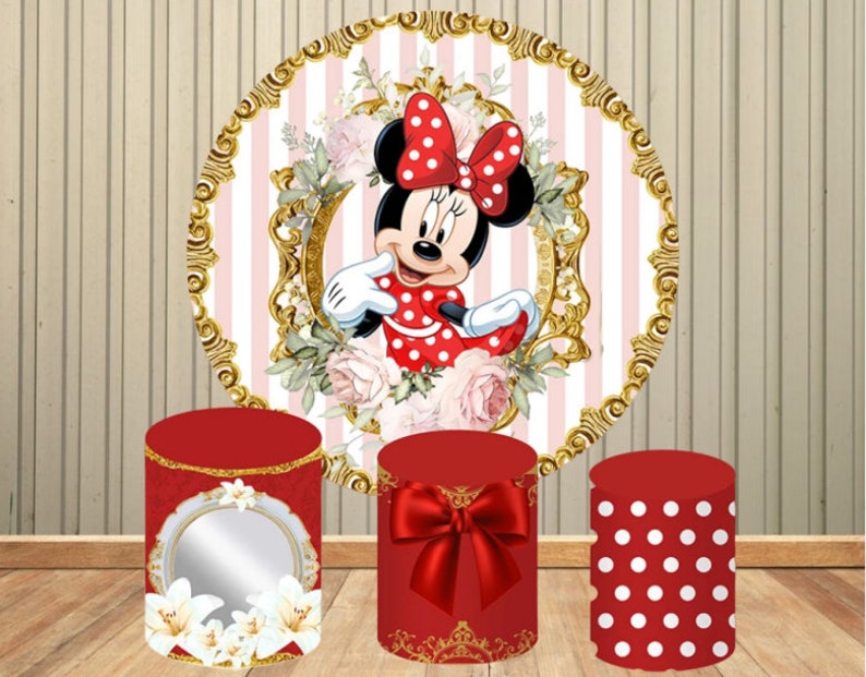 May include: Three red and white themed cake stands with gold accents. The stand on the left has a mirror and white flowers. The middle stand has a red bow. The stand on the right has white polka dots. A round backdrop with a pink and white striped pattern features a cartoon image of Minnie Mouse.