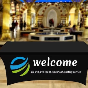 May include: A black table cover displaying the word "welcome" in white, accompanied by a logo with blue and green curved lines. The text "We will give you the most satisfactory service" is also visible.