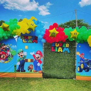 May include: A party backdrop display featuring three arched panels and a central green hedge wall, decorated with colorful balloon arches and gold star balloons. The panels display Super Mario characters and the custom text Super Liam.