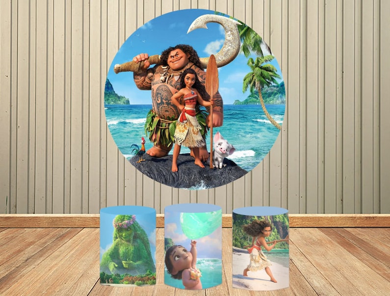 Puede incluir: Un tel&oacute;n de fondo circular con personajes de la pel&iacute;cula animada Moana, incluyendo a Maui, Moana y Pua, ambientado en una escena de playa tropical. Tres soportes cil&iacute;ndricos exhiben im&aacute;genes adicionales de Moana, con personajes como Te Fiti y beb&eacute; Moana.