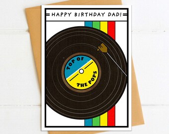 May include: A birthday card with a black vinyl record with a yellow, blue, and white label that says "Top of the Pops". The card has a red, yellow, green, blue, and turquoise stripe pattern on the right side. The card says "Happy Birthday Dad!" at the top.