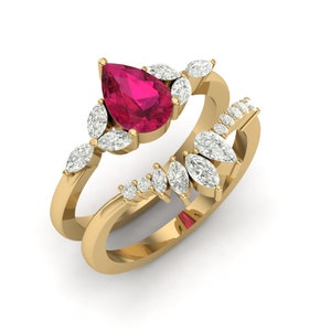 Peut inclure: Un ensemble de bagues en or avec une pierre rouge vif en forme de poire au centre, entourée de pierres blanches en forme de marquise. La monture est également ornée de plus petites pierres blanches, créant un design étincelant et élégant.