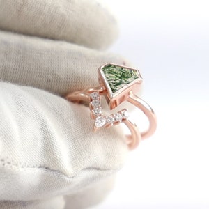 Op de afbeelding: Een ring van roségoud met een groene mosagaat-steen gezet in een geometrische vorm. De ring is versierd met een rij kleine diamanten.