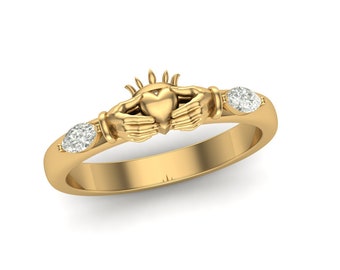 May include: A gold Claddagh ring featuring a heart held by two hands, topped with a crown. The ring has two clear, oval-shaped gemstones on either side of the heart. The ring is set against a white background.