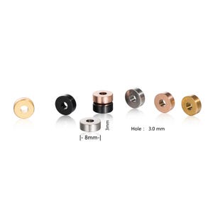 May include: A collection of metallic spacer beads in various colors, including gold, black, silver, copper, and bronze. The beads are cylindrical with a central hole, approximately 8mm in diameter and 3mm thick. The hole size is 3.0 mm.