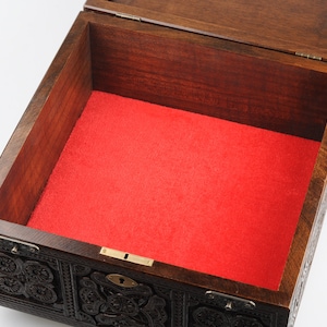 May include: An intricately carved wooden box with a red velvet lining. The box has a brass lock and hinges.