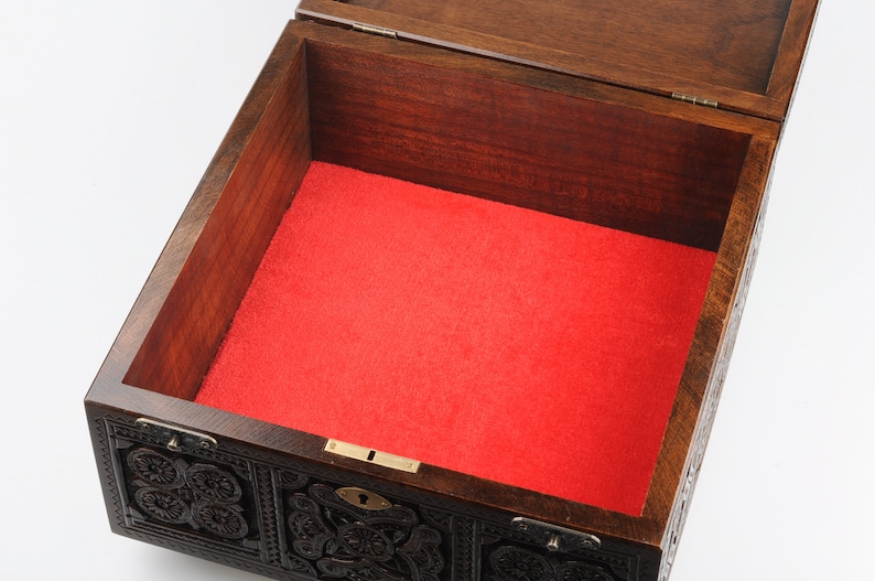 May include: An intricately carved wooden box with a red velvet lining. The box has a brass lock and hinges.