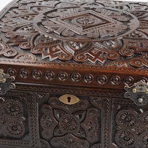 May include: A dark brown wooden box with intricate carvings and brass hinges. The box has a keyhole and a decorative design on the lid.